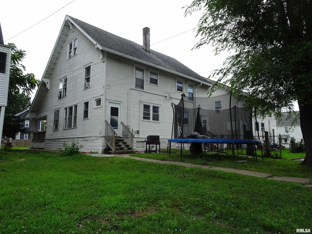 2529-2531 7th Ave, Rock Island, IL 61201 - back of house with entry steps, a trampoline, a lawn, and a chimney
