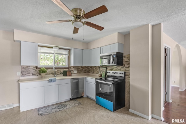 5210 N Division St, Davenport, IA 52806 - kitchen with appliances with stainless steel finishes, tasteful backsplash, light countertops, ceiling fan, and a textured ceiling