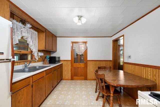 202 Washington Ave, Osco, IL 61274 - kitchen with wainscoting, stainless steel microwave, brown cabinetry, light countertops, and wooden walls