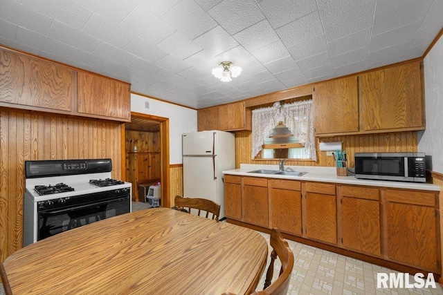 202 Washington Ave, Osco, IL 61274 - kitchen featuring stainless steel microwave, gas range oven, freestanding refrigerator, wood walls, and light countertops