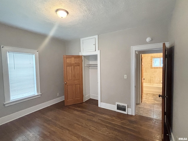 170 16th Ave, East Moline, IL 61244 - unfurnished bedroom featuring dark wood finished floors, a textured ceiling, and a closet
