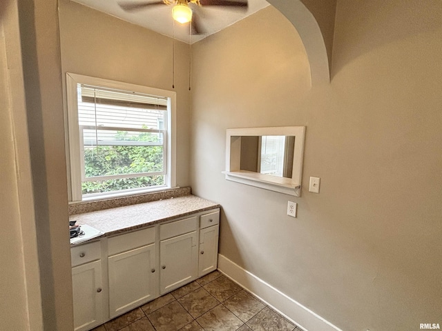 170 16th Ave, East Moline, IL 61244 - interior space featuring ceiling fan, light countertops, tile patterned flooring, white cabinets, and arched walkways