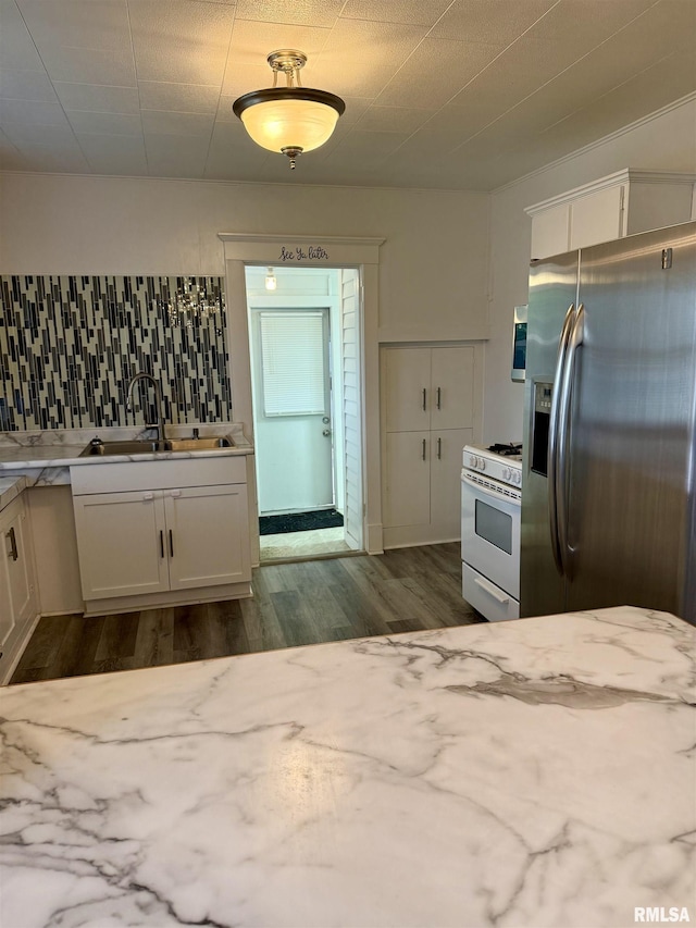 235 20th Pl, Clinton, IA 52732 - kitchen with stainless steel fridge with ice dispenser, white range with gas cooktop, white cabinetry, dark wood finished floors, and decorative backsplash