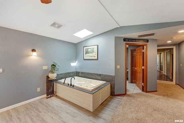 1217 7th St, De Witt, IA 52742 - full bath featuring vaulted ceiling, a whirlpool tub, and wood finished floors