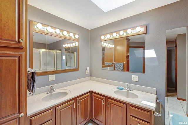 1217 7th St, De Witt, IA 52742 - bathroom featuring tile patterned floors, double vanity, a skylight, and a shower with door