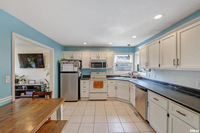 1217 7th St, De Witt, IA 52742 - kitchen with appliances with stainless steel finishes, dark countertops, light tile patterned floors, white cabinetry, and recessed lighting