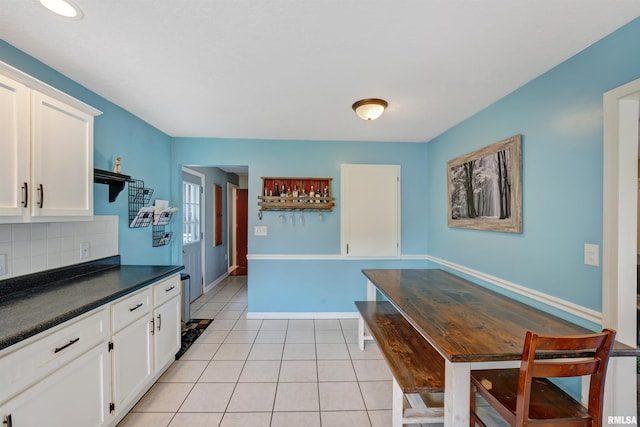1217 7th St, De Witt, IA 52742 - kitchen with white cabinets, dark countertops, light tile patterned floors, and decorative backsplash