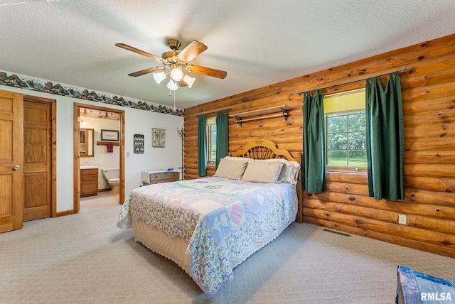 4830 Wyoming Ave, Davenport, IA 52806 - bedroom with log walls, light colored carpet, a textured ceiling, connected bathroom, and a ceiling fan