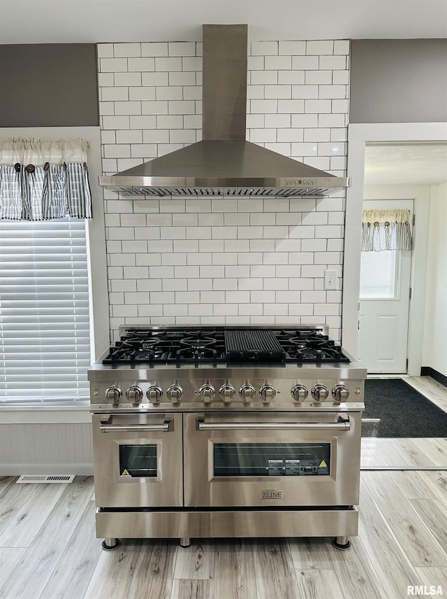 616 Elk St, Sabula, IA 52070 - kitchen featuring range with two ovens, wall chimney exhaust hood, wood finished floors, and backsplash