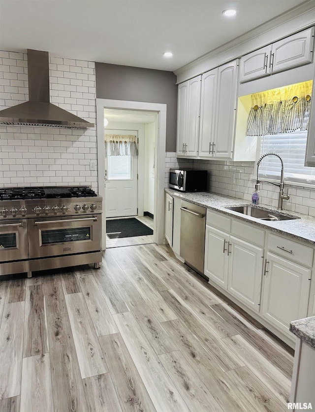 616 Elk St, Sabula, IA 52070 - kitchen with stainless steel appliances, wall chimney exhaust hood, white cabinetry, backsplash, and recessed lighting