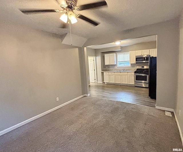 616 1st Ave, Silvis, IL 61282 - kitchen featuring appliances with stainless steel finishes, dark colored carpet, a textured ceiling, a ceiling fan, and white cabinetry