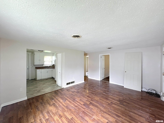 3327 2nd St, East Moline, IL 61244 - unfurnished living room with a textured ceiling and dark wood-type flooring