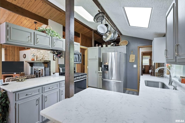 28002 230th St, Le Claire, IA 52753 - kitchen featuring stainless steel appliances, a peninsula, gray cabinetry, wood walls, and light stone countertops