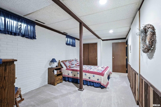 28002 230th St, Le Claire, IA 52753 - bedroom featuring brick wall, carpet flooring, a paneled ceiling, and wainscoting
