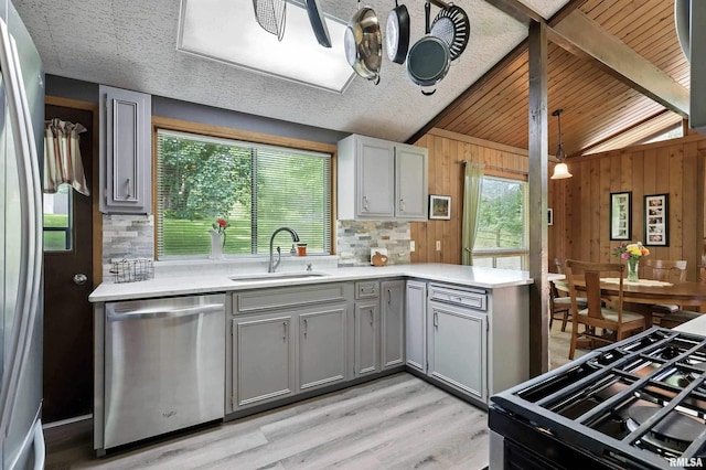 28002 230th St, Le Claire, IA 52753 - kitchen with dishwasher, gray cabinetry, light countertops, light wood-type flooring, and wooden walls