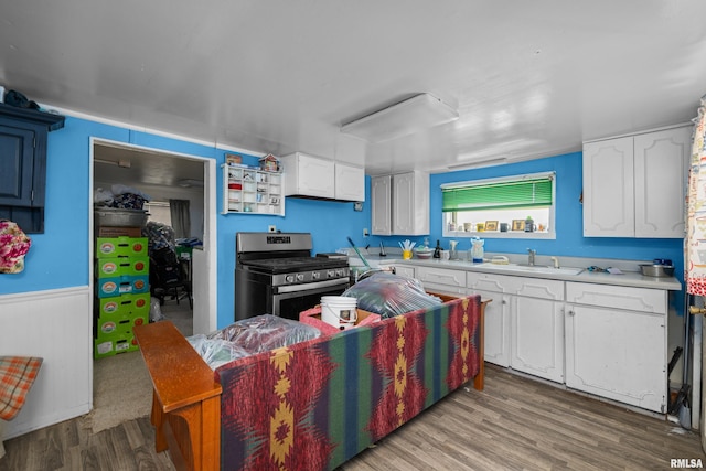 1204 N Cody Rd, Le Claire, IA 52753 - kitchen with gas stove, wood finished floors, white cabinetry, light countertops, and a wainscoted wall