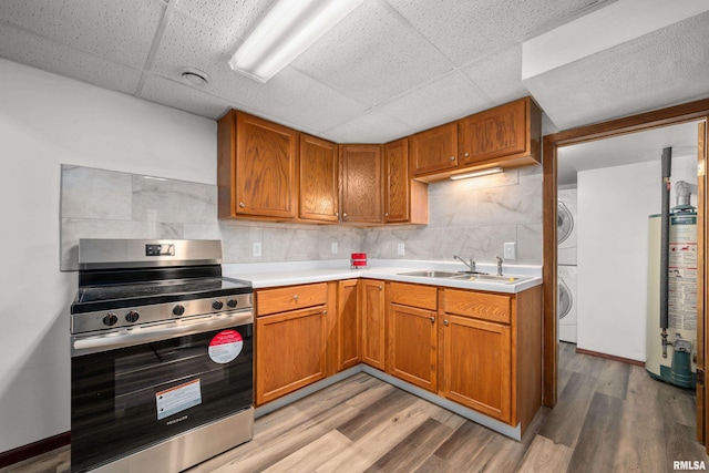 101 W Sheridan Dr, Eldridge, IA 52748 - kitchen with stainless steel electric range oven, stacked washing machine and dryer, a paneled ceiling, gas water heater, and light countertops