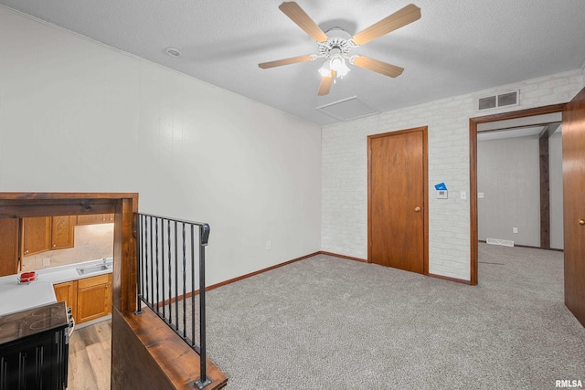 101 W Sheridan Dr, Eldridge, IA 52748 - unfurnished bedroom with brick wall, a textured ceiling, light colored carpet, and ceiling fan