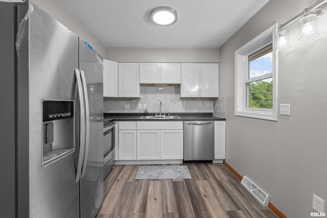 101 W Sheridan Dr, Eldridge, IA 52748 - kitchen with stainless steel appliances, a textured ceiling, tasteful backsplash, dark countertops, and dark wood-type flooring