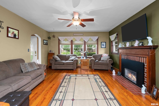 3110 Jefferson Ave, Davenport, IA 52803 - living room with arched walkways, a fireplace, a ceiling fan, and light wood-type flooring