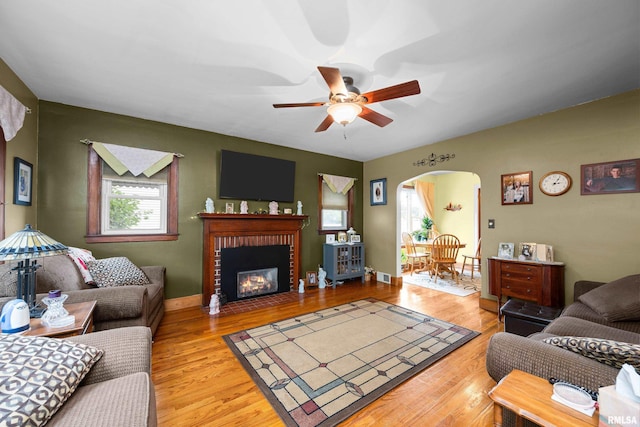 3110 Jefferson Ave, Davenport, IA 52803 - living room featuring arched walkways, ceiling fan, light wood finished floors, and a fireplace