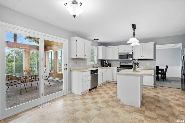 732 W 59th St, Davenport, IA 52806 - kitchen with stainless steel appliances, light countertops, white cabinetry, a center island, and pendant lighting