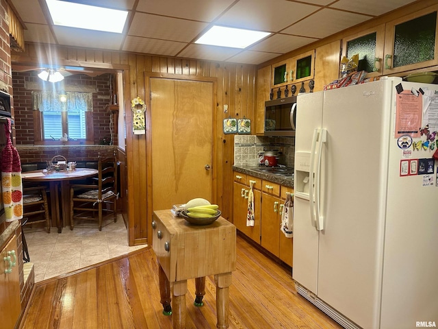 1723 Pershing Blvd, Clinton, IA 52732 - kitchen featuring white refrigerator with ice dispenser, stainless steel microwave, brown cabinetry, light wood-style flooring, and stovetop