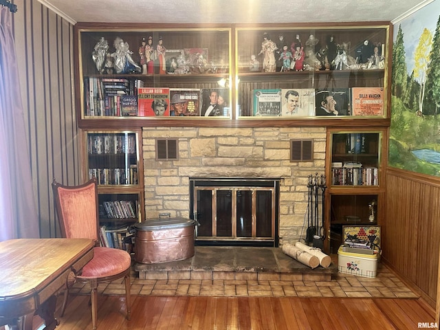 1723 Pershing Blvd, Clinton, IA 52732 - living area featuring crown molding, wood-type flooring, wood walls, a fireplace, and a textured ceiling
