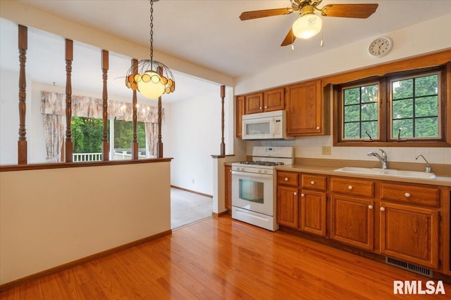 17223 N Cedar Rd, East Moline, IL 61244 - kitchen featuring white appliances, brown cabinets, light wood-type flooring, light countertops, and backsplash