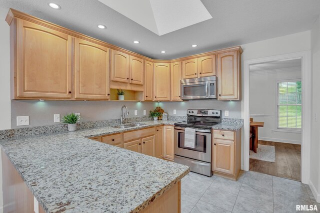 1039 Bluff Ln, Le Claire, IA 52753 - kitchen with appliances with stainless steel finishes, light brown cabinetry, a peninsula, recessed lighting, and light stone counters