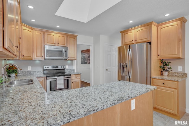 1039 Bluff Ln, Le Claire, IA 52753 - kitchen featuring appliances with stainless steel finishes, light brown cabinets, a skylight, light stone countertops, and a peninsula