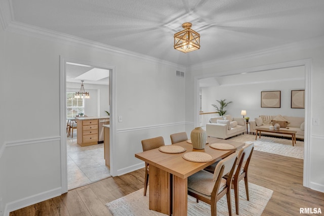 1039 Bluff Ln, Le Claire, IA 52753 - dining area featuring a chandelier, light wood finished floors, and ornamental molding