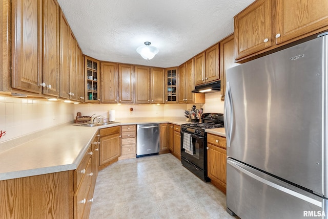 13118 65th Ave, Blue Grass, IA 52726 - kitchen with appliances with stainless steel finishes, brown cabinetry, under cabinet range hood, light countertops, and glass insert cabinets