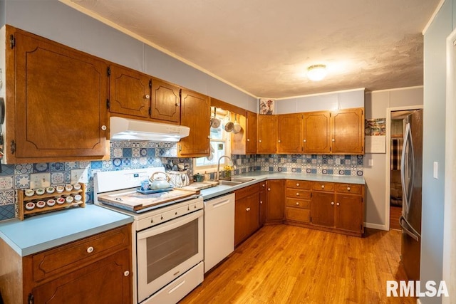 17000 Log Cabin Rd, Marion, IL 62959 - kitchen featuring white appliances, under cabinet range hood, light wood-style flooring, brown cabinetry, and tasteful backsplash