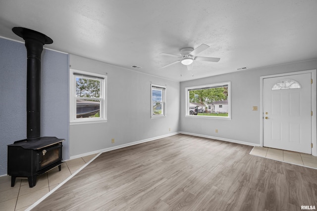 1671 US Highway 67, Preemption, IL 61276 - unfurnished living room with a wood stove, plenty of natural light, a ceiling fan, wood finished floors, and a textured ceiling