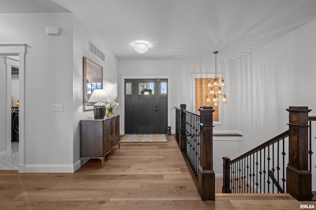 5835 Pigeon Creek Rd, Bettendorf, IA 52722 - foyer entrance with light wood-type flooring, washer / clothes dryer, and a chandelier