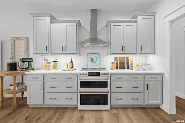 5835 Pigeon Creek Rd, Bettendorf, IA 52722 - kitchen with double oven range, wall chimney exhaust hood, light countertops, and decorative backsplash