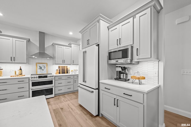 5835 Pigeon Creek Rd, Bettendorf, IA 52722 - kitchen with premium appliances, wall chimney range hood, light wood-style flooring, tasteful backsplash, and light countertops