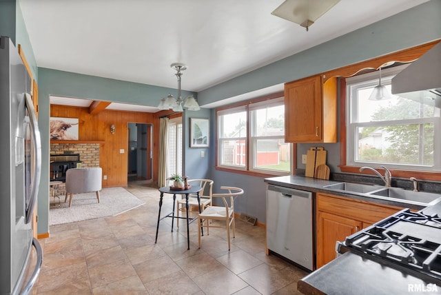 505 N 7th St, Eldridge, IA 52748 - kitchen featuring stainless steel appliances, wooden walls, dark countertops, brown cabinetry, and hanging light fixtures