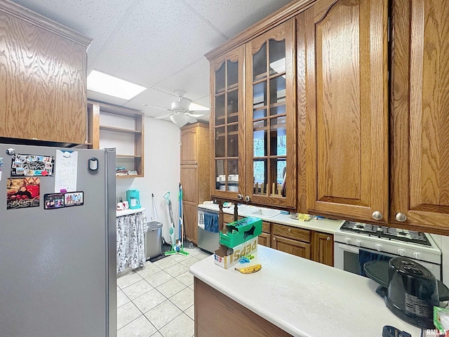 1426 32nd St, Rock Island, IL 61201 - kitchen with freestanding refrigerator, a drop ceiling, light tile patterned flooring, brown cabinetry, and a ceiling fan