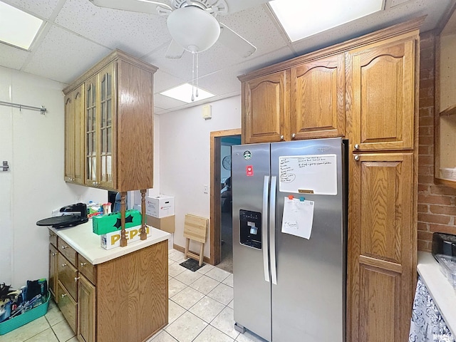 1426 32nd St, Rock Island, IL 61201 - kitchen featuring stainless steel fridge, ceiling fan, glass insert cabinets, a paneled ceiling, and light countertops