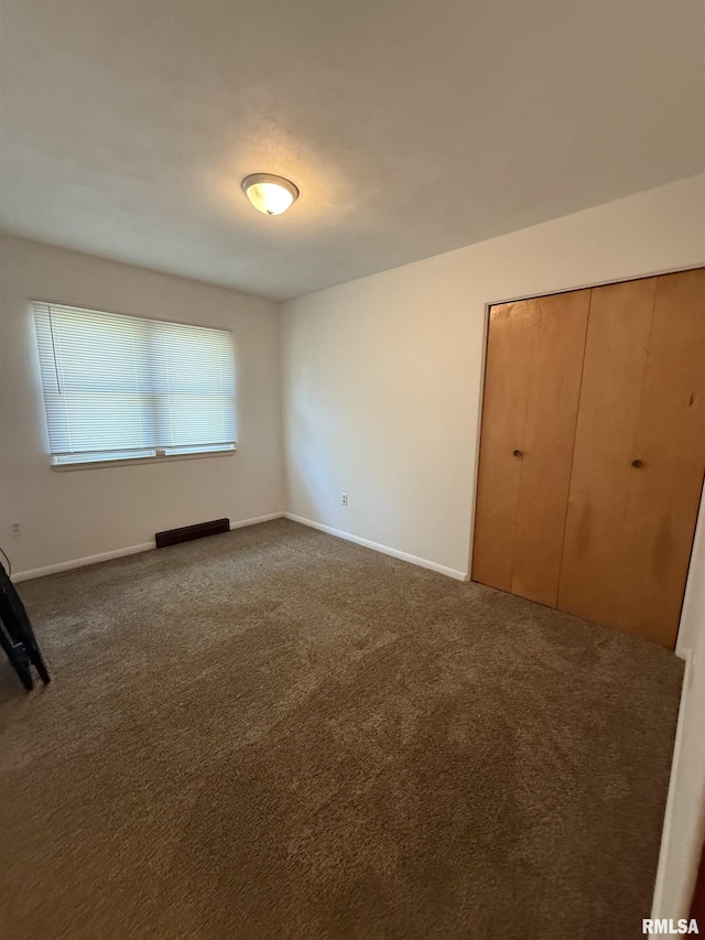 302 E Ames St, Yates City, IL 61572 - unfurnished bedroom featuring dark colored carpet and a closet