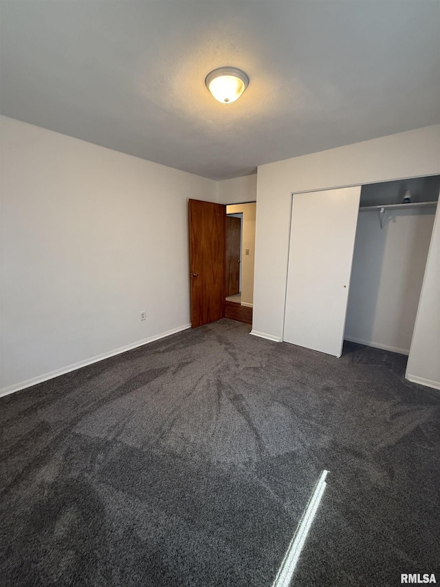 302 E Ames St, Yates City, IL 61572 - unfurnished bedroom featuring dark colored carpet and a closet