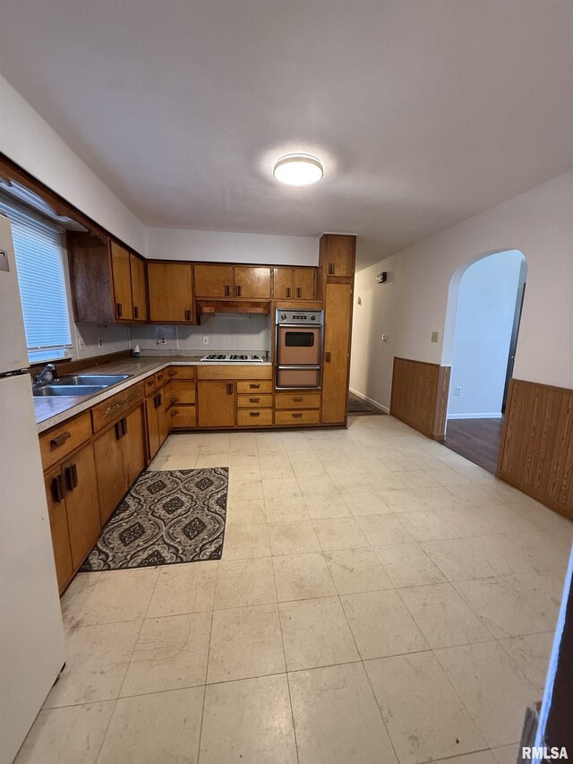 302 E Ames St, Yates City, IL 61572 - kitchen with stainless steel oven, gas stovetop, a warming drawer, freestanding refrigerator, and brown cabinetry