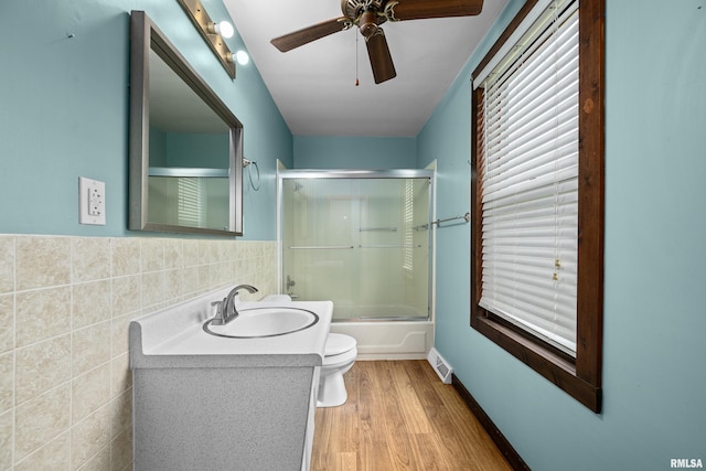 404 5th St, Sherrard, IL 61281 - full bath with ceiling fan, shower / bath combination with glass door, wood finished floors, vanity, and tile walls