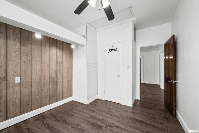 404 5th St, Sherrard, IL 61281 - unfurnished bedroom featuring attic access, dark wood-type flooring, ceiling fan, wood walls, and a closet