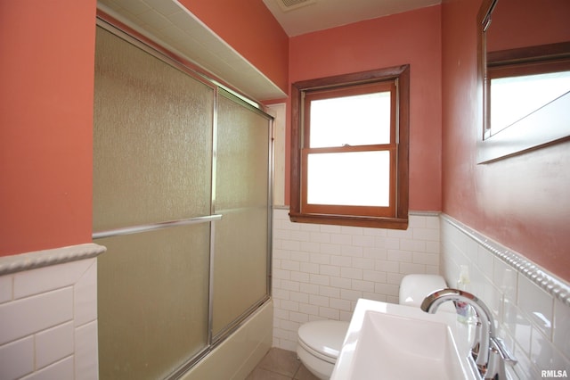 1524 W 4th St, Milan, IL 61264 - full bath featuring tile walls, shower / bath combination with glass door, tile patterned flooring, and a wainscoted wall
