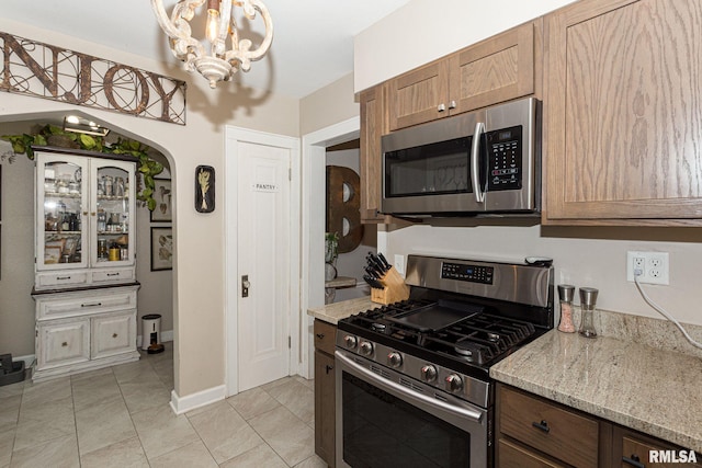3205 Crestline Dr, Davenport, IA 52803 - kitchen featuring appliances with stainless steel finishes, a chandelier, light stone counters, and light tile patterned flooring