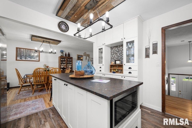 833 Robin Rd, Muscatine, IA 52761 - kitchen with stainless steel microwave, a chandelier, dark countertops, white cabinets, and dark wood-type flooring