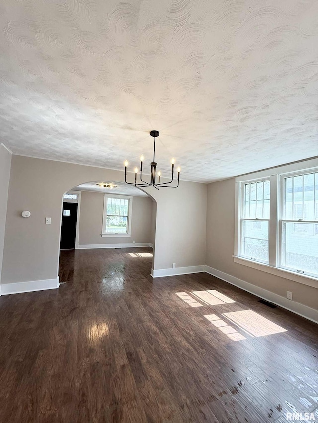 2111 Pine St, Murphysboro, IL 62966 - unfurnished living room featuring arched walkways, a chandelier, a textured ceiling, and dark wood-type flooring